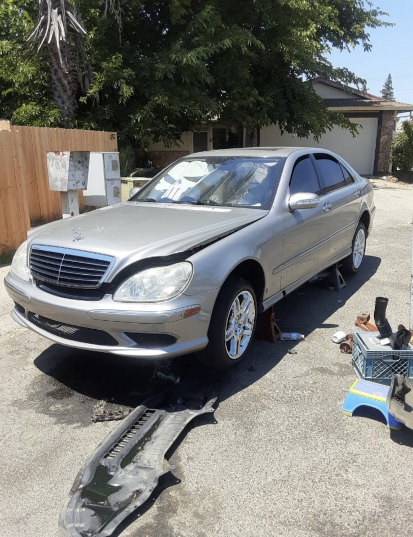 Mobile mechanic working on a silver Mercedes-Benz sedan in a residential driveway in Anaheim
