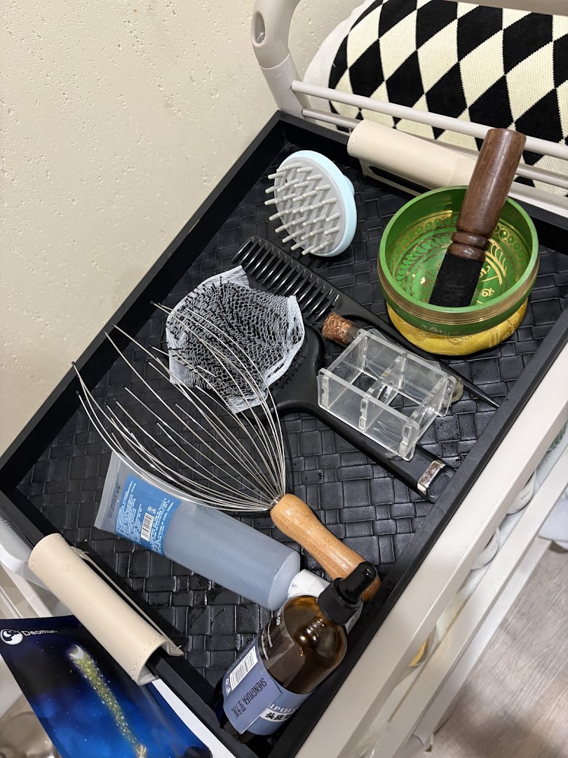 Scalp treatment tools detail — head massager, brushes, and oil applicators arranged on a textured tray